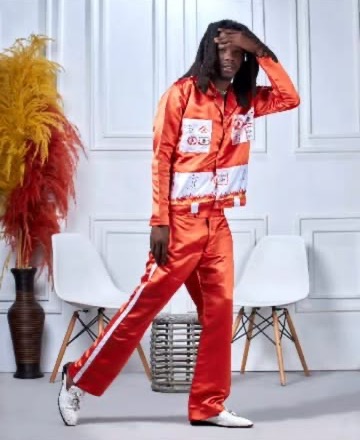 Man in an orange satin patch set posing in a white studio