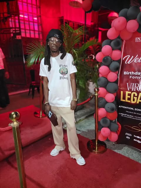Man in a white Richer Than Money tee on a red carpet