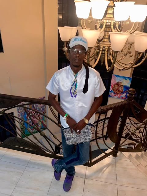 Man in a white silk shirt and printed scarf by a chandelier